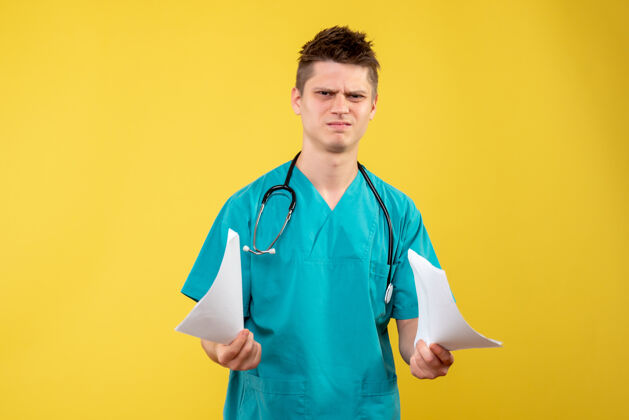 听诊器黄色墙壁上的男医生穿着医疗服的正面图医生分析人