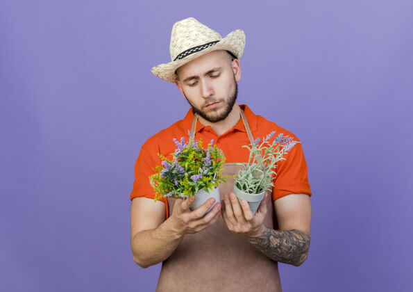 帽子困惑的男园丁戴着园艺帽拿着花盆看男花园举行
