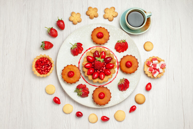 食物俯瞰图：白色桌子上有水果蛋糕和一杯茶餐厅甜点盘子