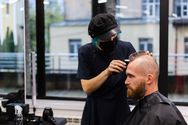 理发师专业美发师戴着防护面罩 在美容院为欧洲胡须野蛮男子理发男人发型师男性