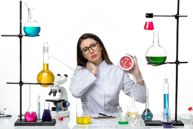 人前视图穿着白色医疗服的女化学家手持浅白色背景上的红色时钟科学病毒冠状病毒-大流行实验室医疗西装大流行