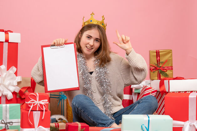 礼物正面图年轻女性围坐在礼物旁边 手里拿着纸条年轻的女性年礼物