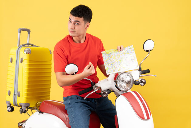 男性前视图骑着摩托车的帅哥拿着黄色的地图前面黄色轻便摩托车