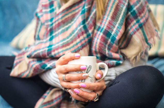 冬天坐着的时候 一个女人手里拿着一杯咖啡 穿着暖和的冬装纺织品咖啡馆豆类