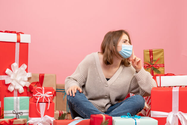 人正面图：年轻女性戴着面具围坐在圣诞礼物旁边礼物微笑成人