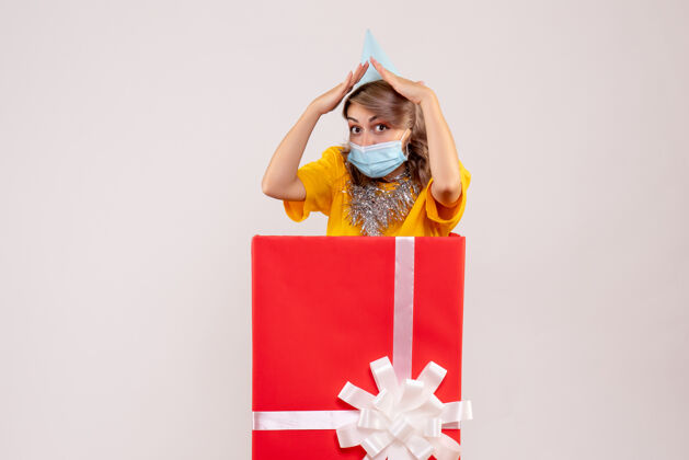 年正面图：戴着面具的红色礼品盒里的年轻女性圣诞女士盒子