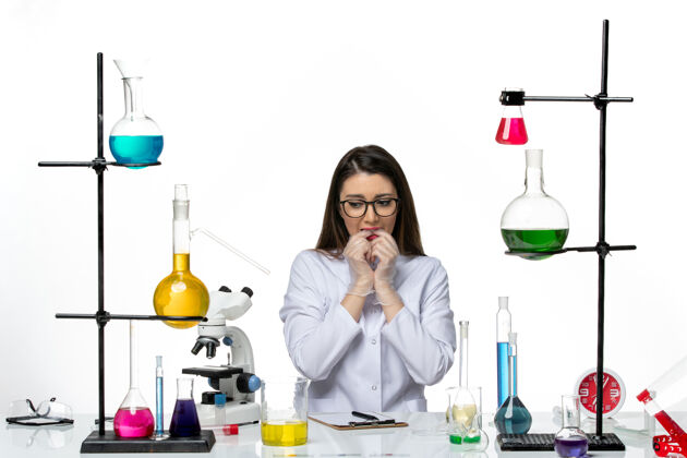 病毒前视图穿着白色医疗服的女化学家坐在白色背景上紧张不安实验室科学病毒冠状病毒大流行实验室感觉玻璃
