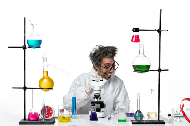 科学前视图穿着特殊防护服的疯狂男科学家围坐在桌子旁 拿着白色办公桌上的实验室疾病冠状病毒科学病毒的解决方案实验室坐着桌子