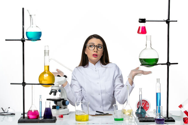套装前视图穿着白色医疗服的女化学家坐在白色背景上解决方案科学大流行病毒covid实验室玻璃正面科学