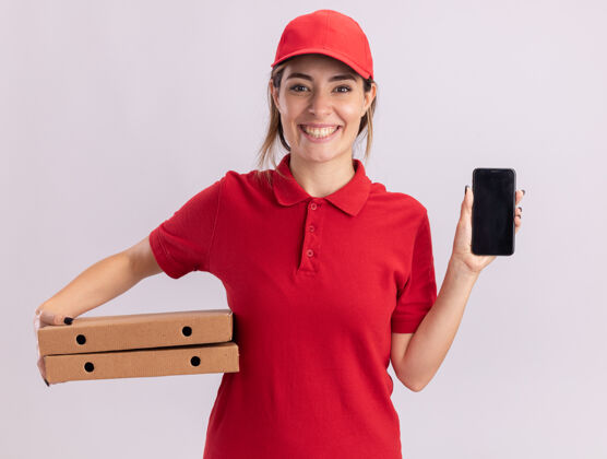 人微笑着的年轻漂亮的送货女孩穿着制服拿着比萨饼盒和白色的电话成人年轻人漂亮
