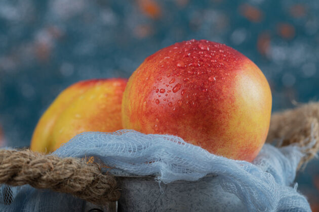 艺术红色的桃子被隔离在蓝色的厨房毛巾上季节酸热带