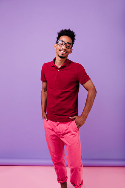 紫色快乐的黑人男模站在自信的姿势微笑无忧无虑的男子在粉红色裤子和红色t恤冷放松舞蹈乐观