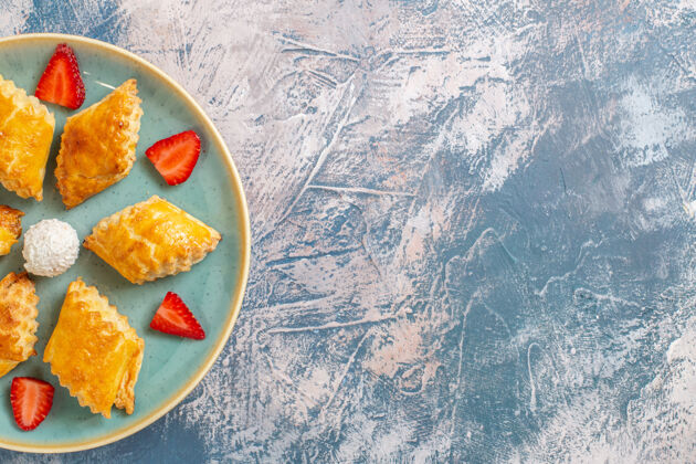 草莓俯瞰美味的甜蛋糕与草莓蓝色背景水午餐胡椒