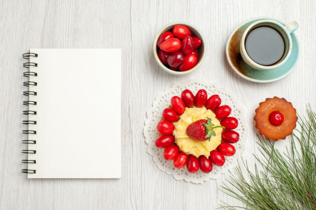 桌子俯瞰白色桌子上的水果蛋糕和一杯茶减肥番茄浆果