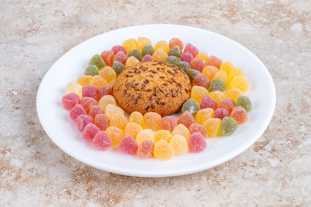 水果石头桌上放着一盘白色的燕麦片饼干和甜果冻糖口香糖耐嚼水果