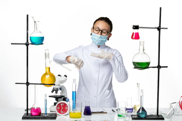 面具前视图穿着医疗服的女化学家戴着口罩看着她手腕上白色背景的病毒化学实验室病毒飞溅实验室专业手腕