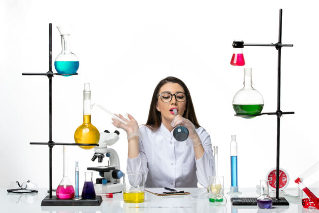 瓶子前视图：穿着白色医疗服的女化学家拿着白色背景上蓝色溶液的烧瓶实验室科学病毒共价病毒-大流行视图药品病毒