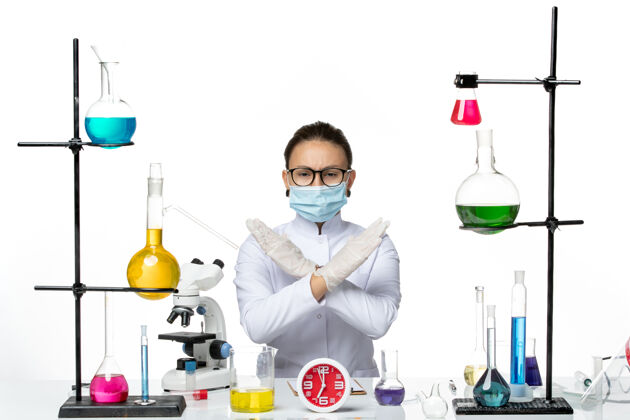 喷溅前视图穿着白色医疗服的女化学家带着面罩坐着 溶液显示白色背景上的禁止标志化学家病毒covid-飞溅实验室实验室实验室解决方案