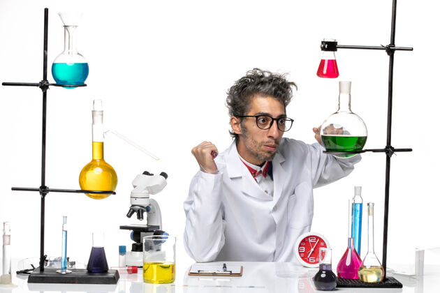 化学正面图身穿医疗服的男科学家坐在桌子前 白色办公桌上摆着解决方案科维德实验室病毒健康化学桌子解决方案视图