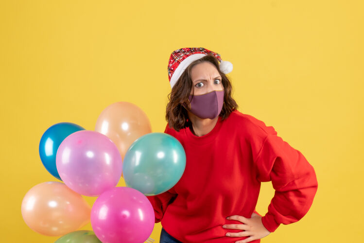 面具正面图年轻女性拿着气球 戴着黄色的无菌面具年轻女性乐趣颜色