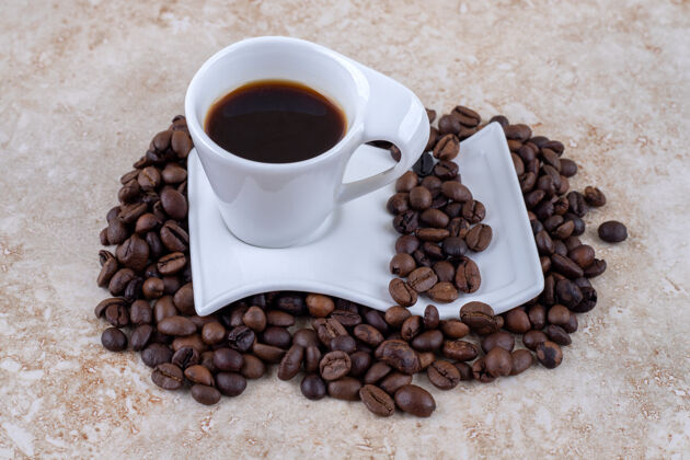 咖啡坐在一堆咖啡豆上的茶碟上的一杯咖啡芳香茶碟