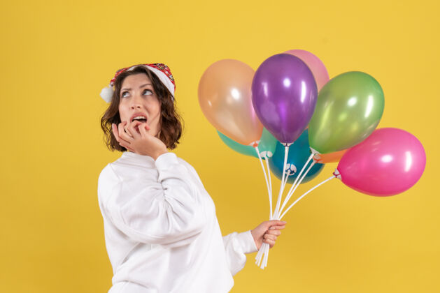 多彩正面图美丽的女性手持五颜六色的气球站在黄色生日空气节日