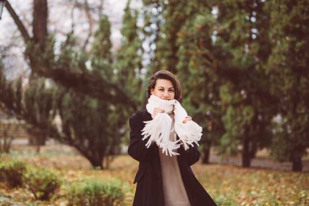 优雅公园里穿着冬天黑外套白围巾的女人的户外肖像黑色女孩秋天