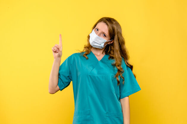 专业黄墙上戴着面具的女医生的正视图微笑漂亮医学