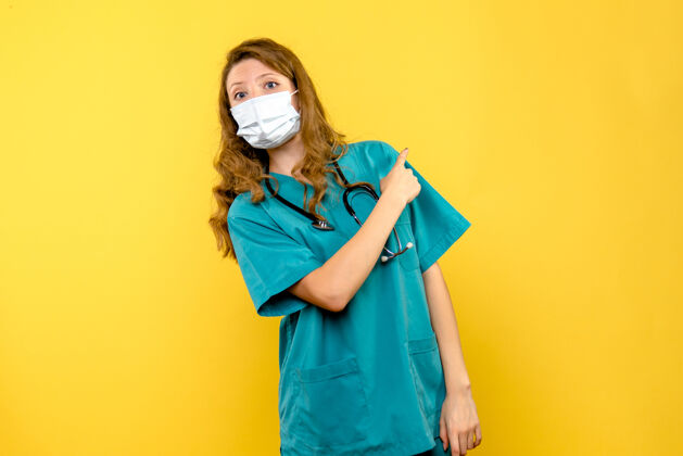 医院黄墙上戴着面具的女医生的正视图快乐可爱女医生