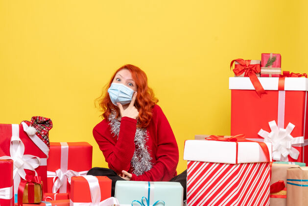 病毒正面图漂亮的女性围坐在黄色的面具上展示礼物年份前面圣诞节