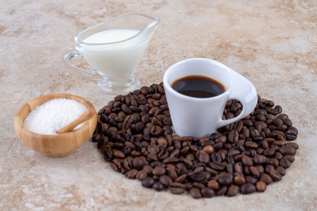 排列小碗糖旁边有一堆咖啡豆围着一杯咖啡咖啡芳香美味