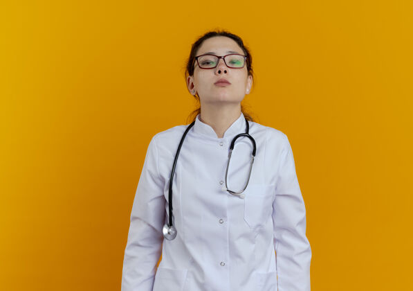 年轻人自信的年轻女医生穿着医用长袍和听诊器 戴着眼镜成年人穿着橙色