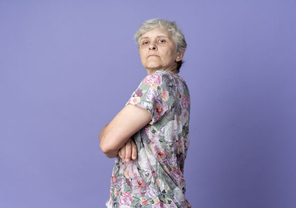 站着自信的老妇人侧身站在紫色的墙上 看上去孤立无援侧身老老