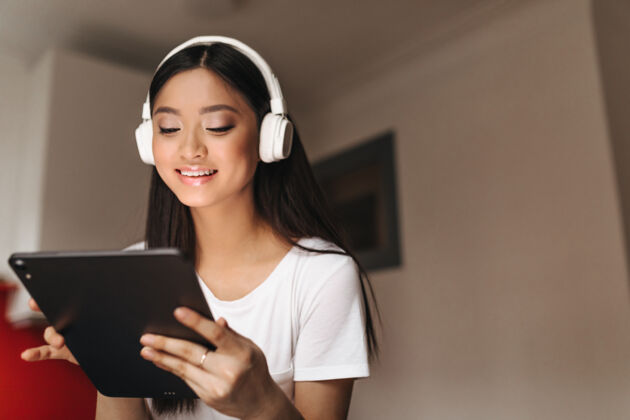 互联网迷人的亚洲女人微笑着看着平板电脑现代空气移动