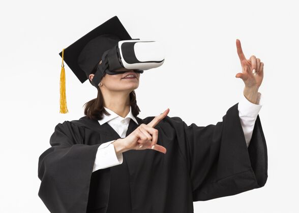 毕业帽穿着毕业礼服戴毕业帽戴着虚拟现实耳机的女人虚拟现实技术模特
