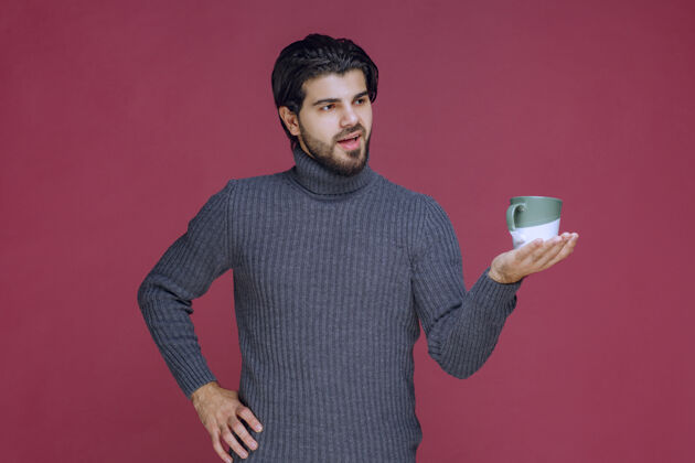 姿势一个穿着灰色毛衣的男人手里拿着一个咖啡杯休闲性感工人