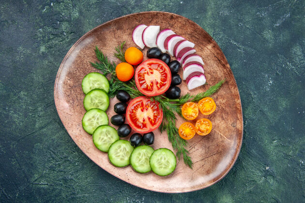 农产品新鲜切碎的蔬菜橄榄金橘在绿黑色混合色背景上的棕色盘子的顶视图金橘盘子饮食