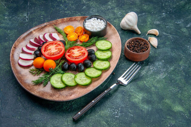 蔬菜侧视图新鲜切碎的蔬菜橄榄在一个棕色的盘子和叉子胡椒大蒜素绿黑色混合色背景食物晚餐盘子