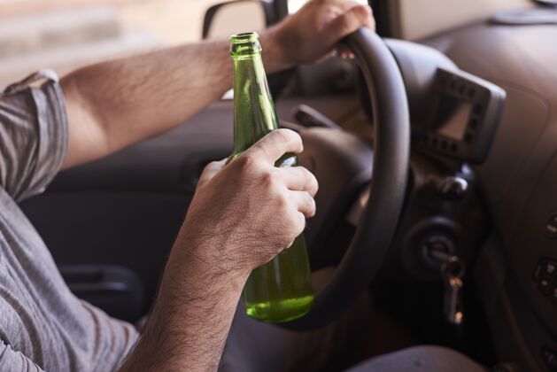 汽车白天开车的男人手里拿着一瓶啤酒液体休闲冷的