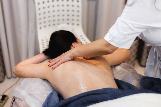 皮肤科在spa沙龙接受背部和颈部按摩的女孩 躺在美容台上 放松享受这个过程服务护理水疗