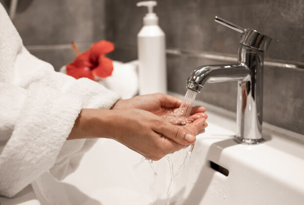 清洗一个穿着长袍的女人在自来水下洗手水龙头卫生手