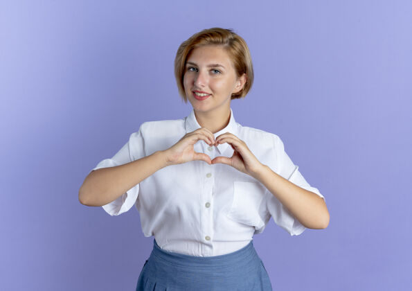 手年轻的微笑金发俄罗斯女孩手势心手标志孤立的紫色背景与复制空间手势俄罗斯年轻