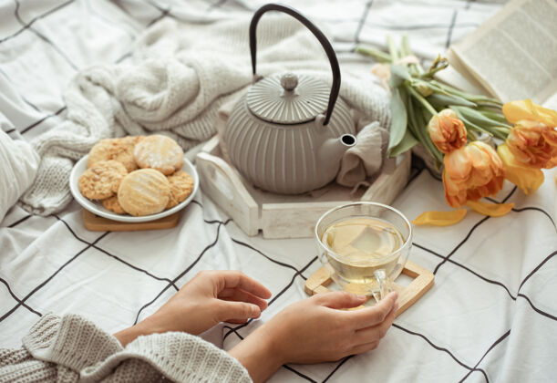 静物一杯茶 一个茶壶 一束郁金香和饼干躺在床上静物周末和春天的早晨的概念房子周末饼干