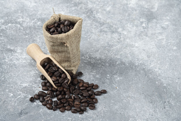 浓缩咖啡装满烤咖啡豆的麻布和放在大理石表面的木勺香味豆类烤