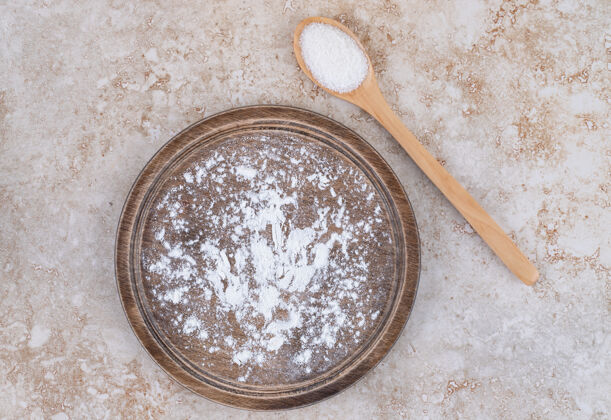 平面一盘棕色的面粉和一把木勺糖烹饪蛋白质面粉