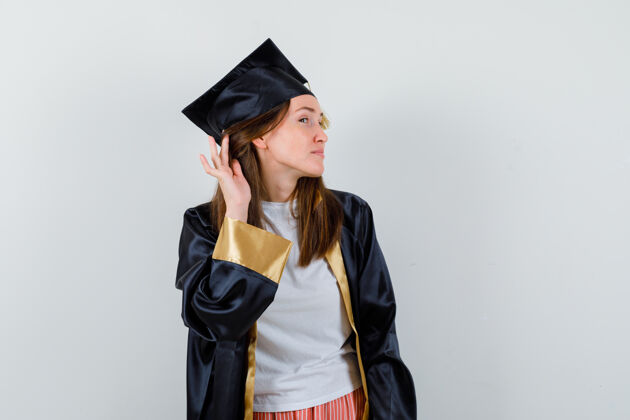 人民女毕业生穿着制服 手放在耳朵后面 穿着休闲服 看上去很好奇正面图学位保持衣服