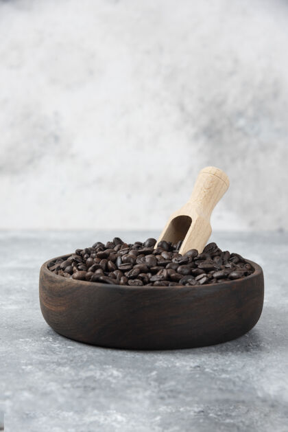 烤木制碗中烤咖啡与勺子大理石表面咖啡浓烈的