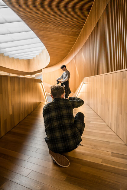 摄影师身穿黑白格子衬衫的男子坐在棕色木地板上拍照模特拍照照相机