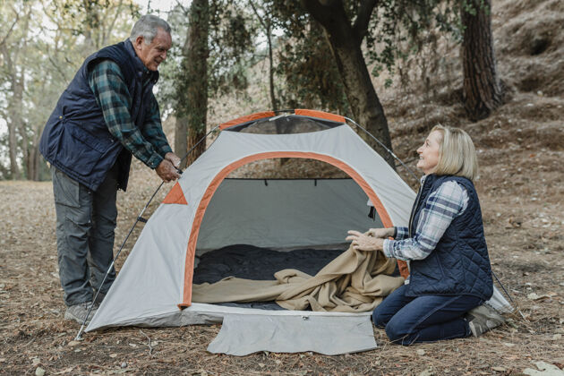 老人快乐的老年夫妇在森林里搭帐篷野生祖父退休