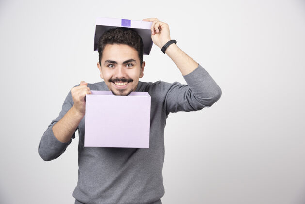 人带着微笑的男人 在白色的墙上放着一个打开的紫色盒子男孩男人紫色